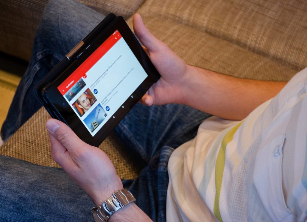 A transição dos "normais" 1 Imagem de uma pessoa assistindo vídeos no YouTube usando um tablet. Fim da descrição.